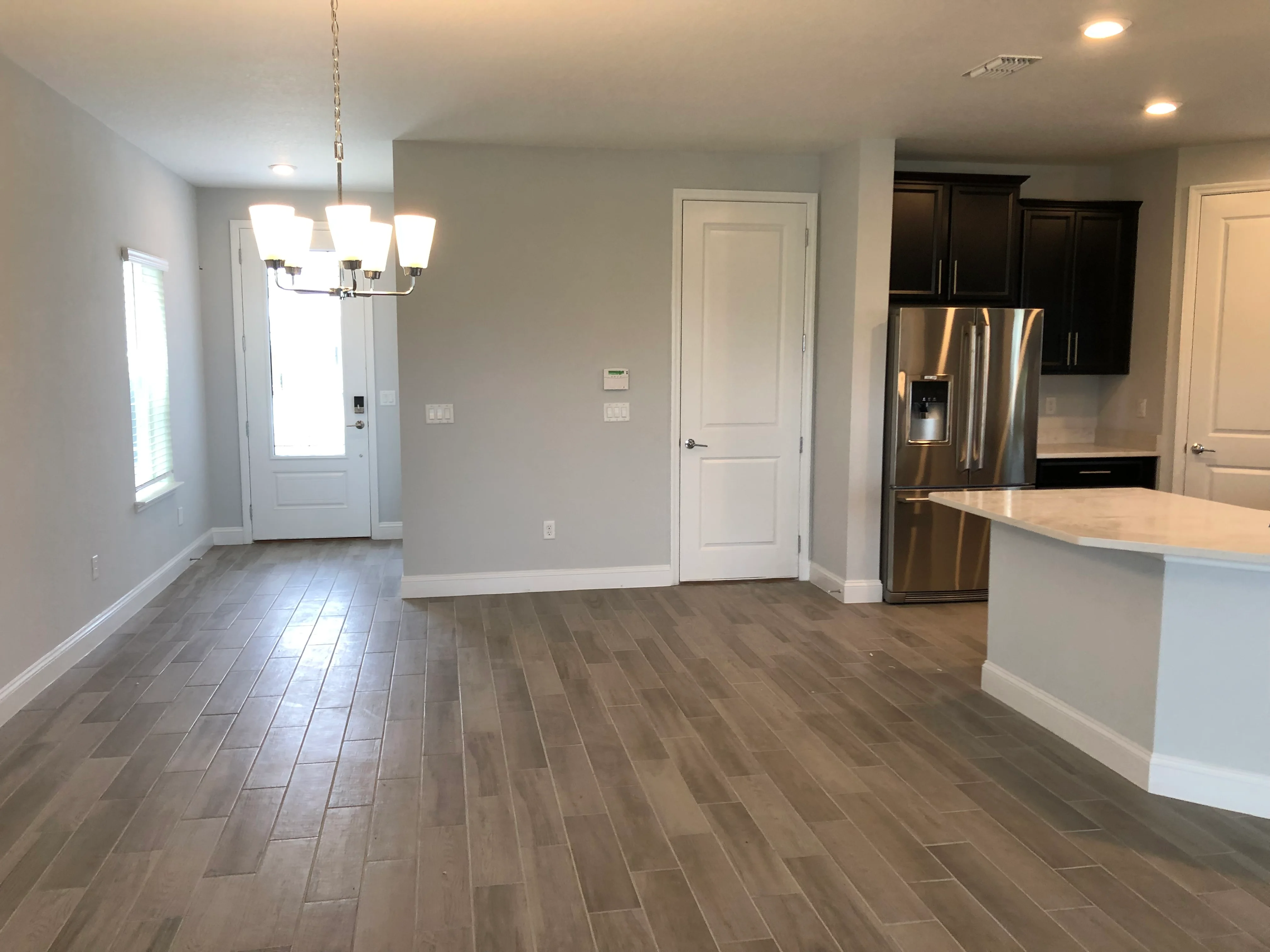Modern kitchen with stainless steel appliances, white island, and plank flooring