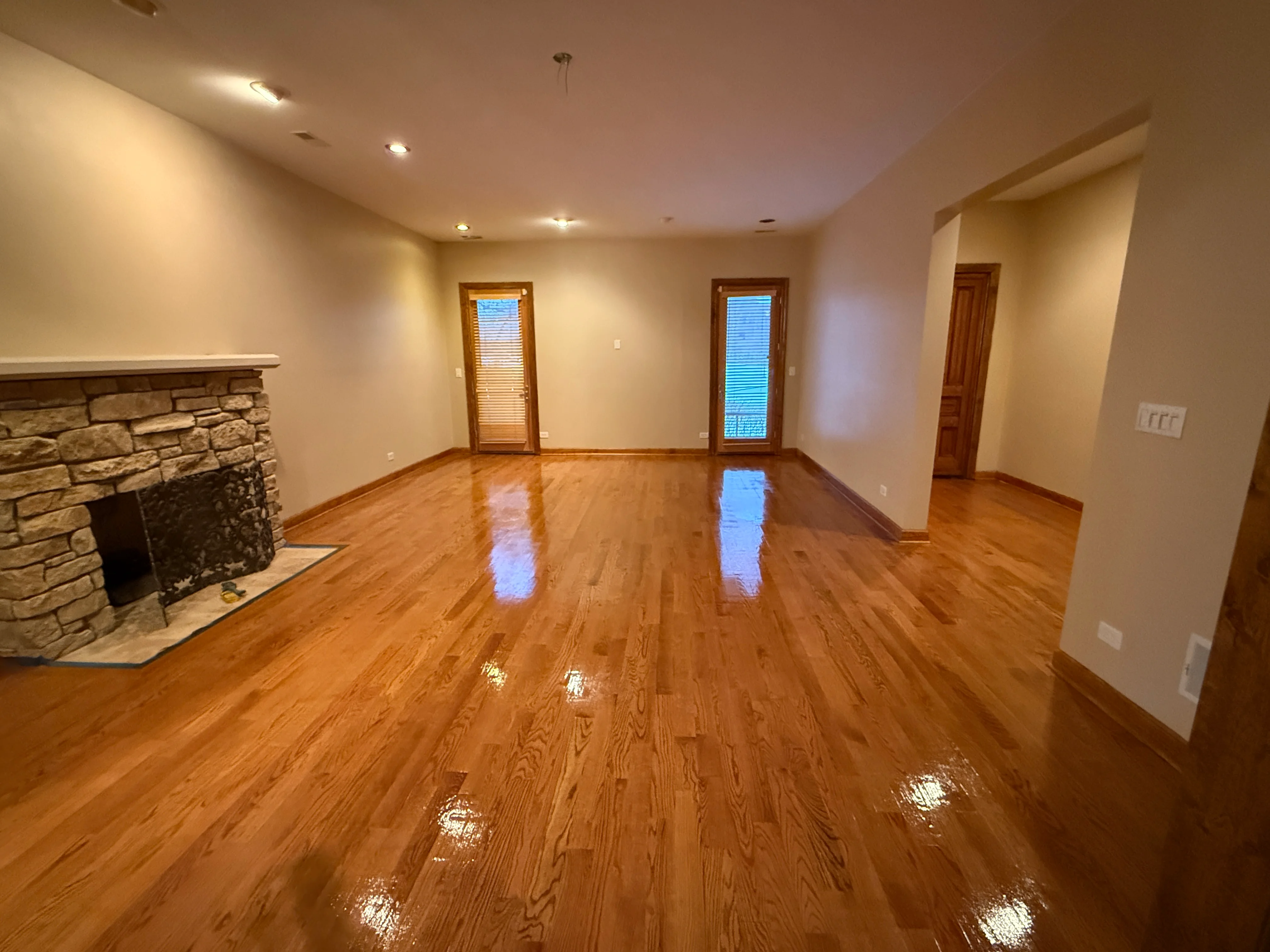 Finished basement with gleaming hardwood floors, stone fireplace, and recessed lighting