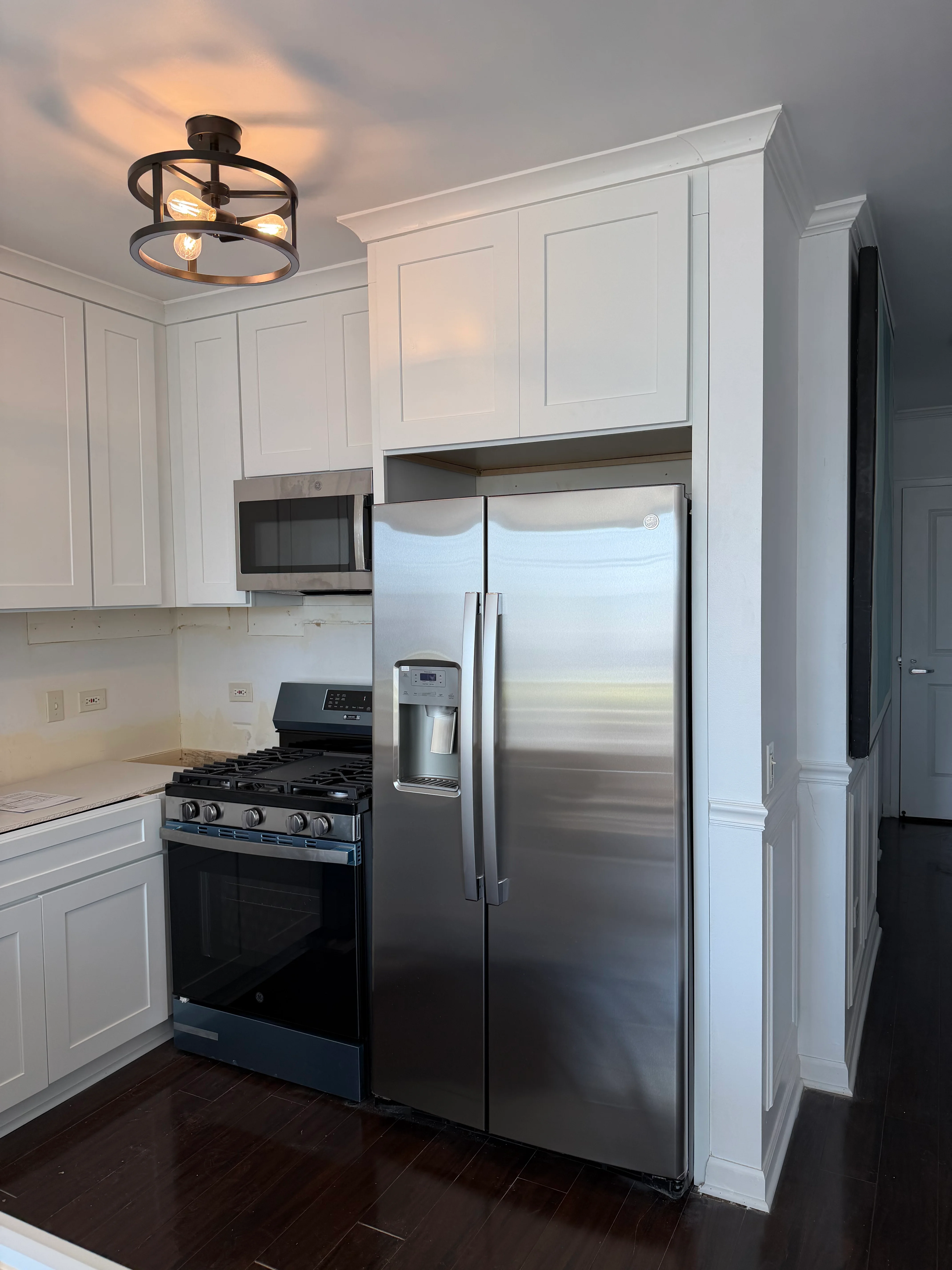 Modern kitchen with white cabinetry, stainless steel appliances, and dark hardwood floors