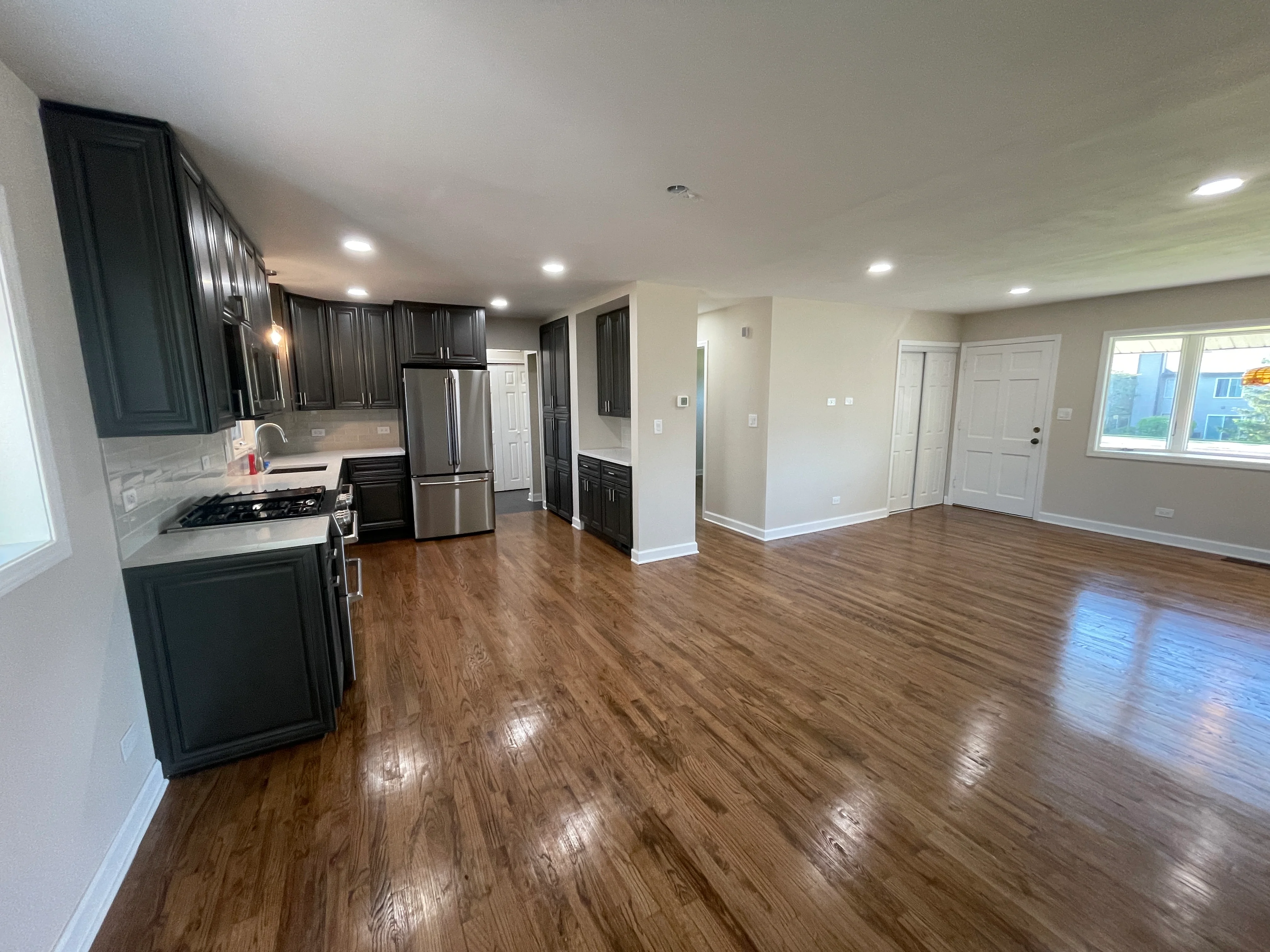 Modern kitchen with dark cabinetry, stainless steel appliances, and hardwood flooring