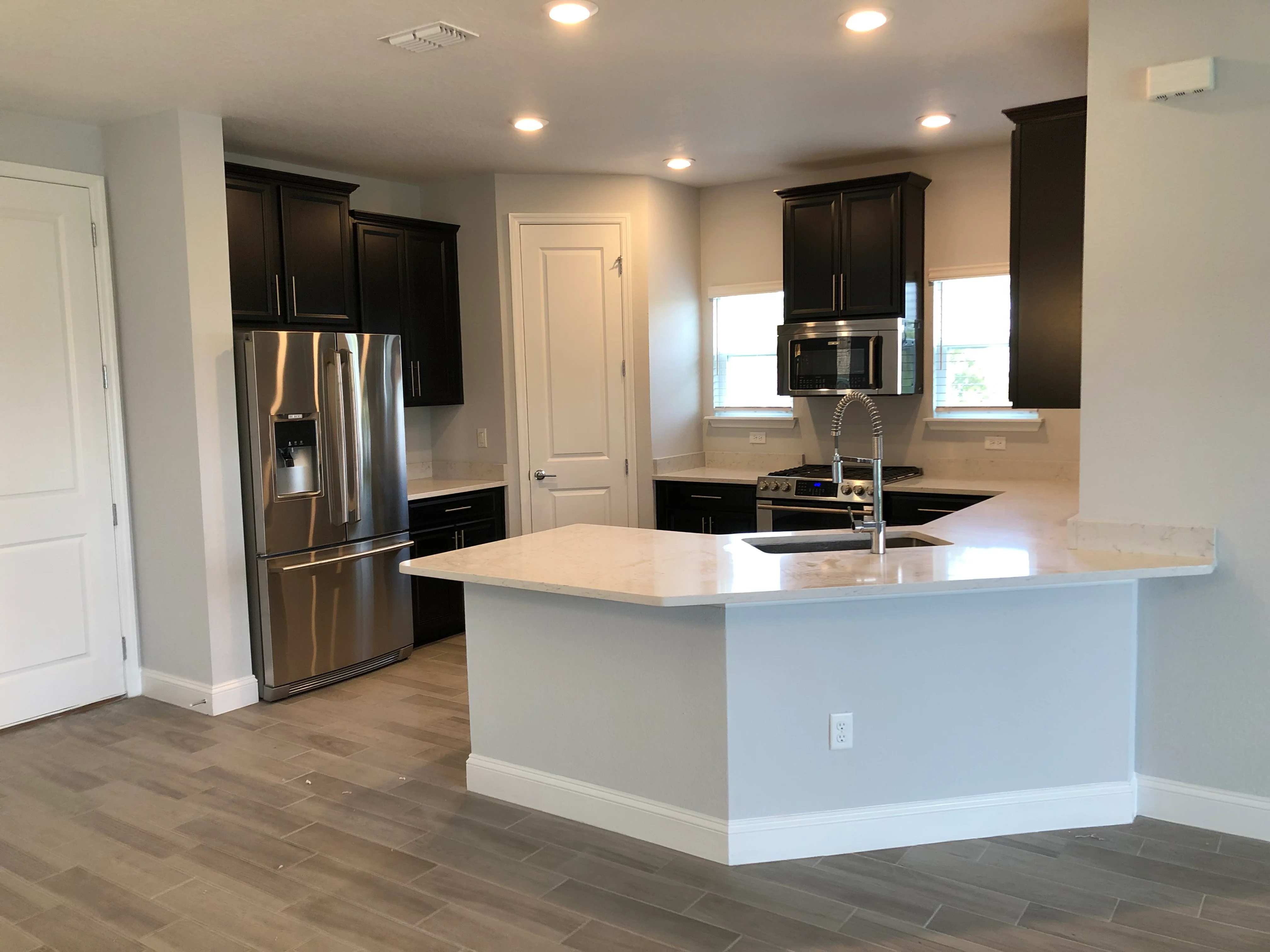 Modern kitchen with black cabinets, white island, and stainless steel appliances