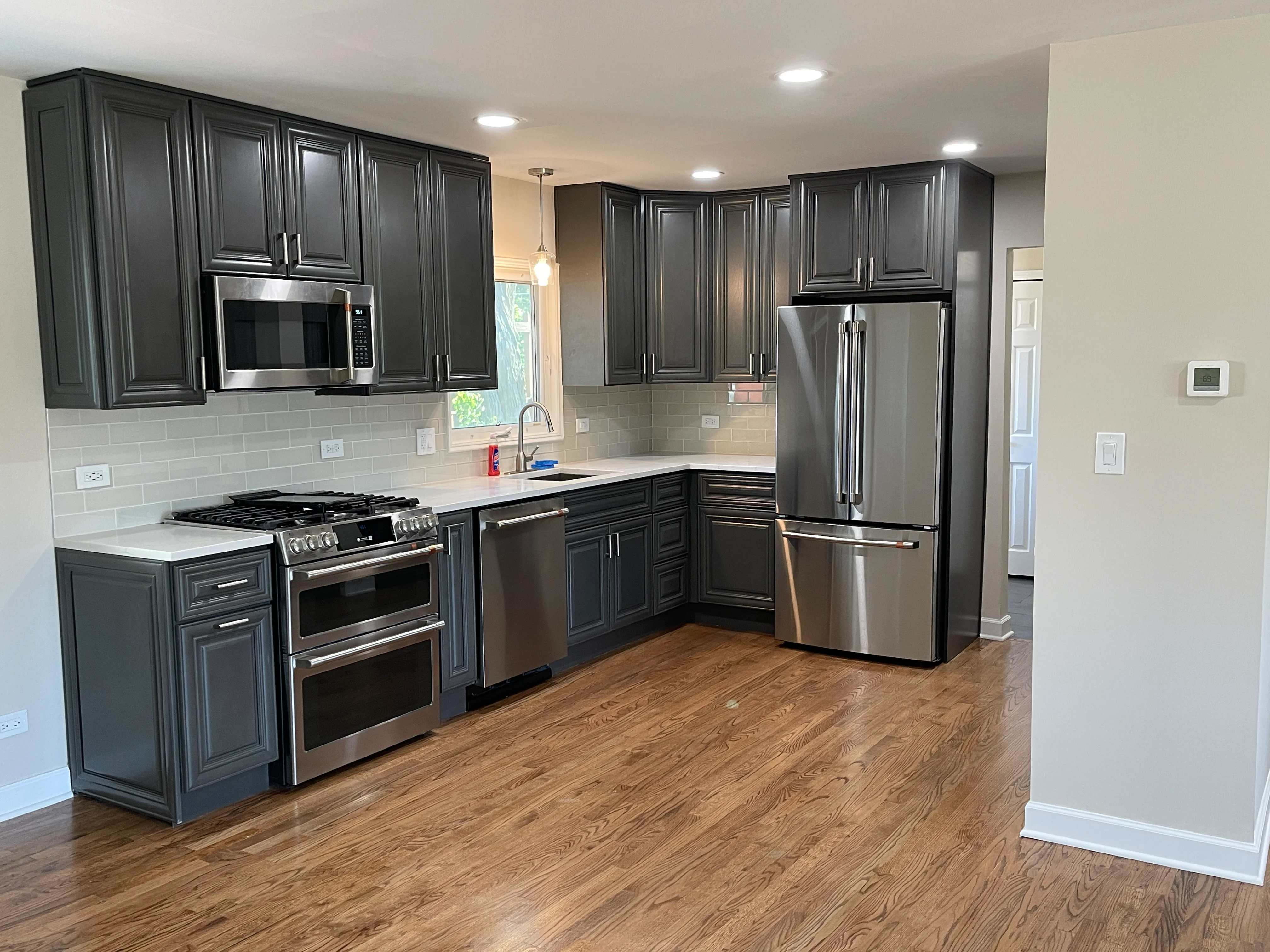 Modern kitchen with dark gray cabinets, stainless steel appliances, and white subway tile backsplash