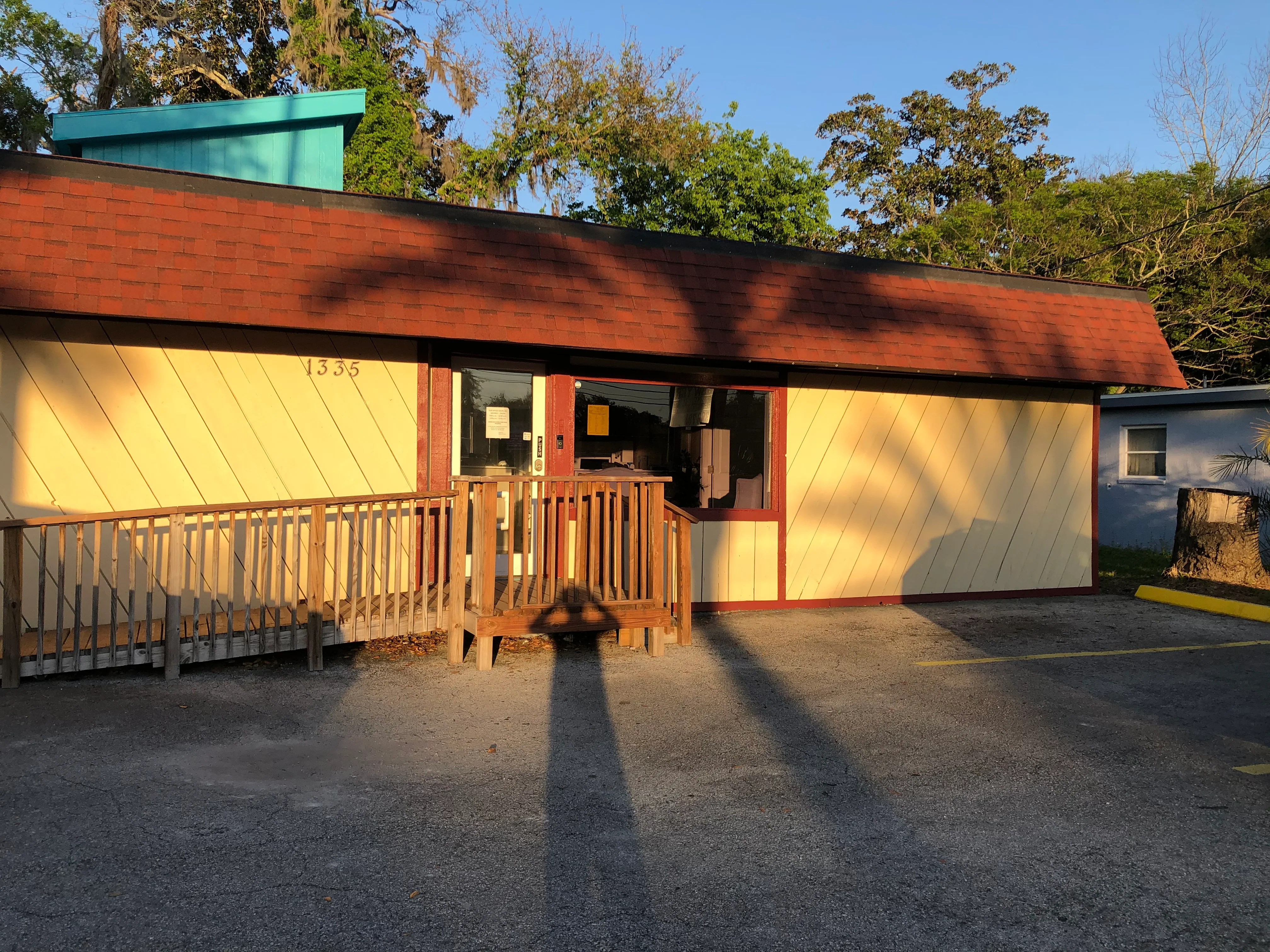 Renovated mid-century commercial building with yellow siding, red brick, and new wooden deck entry