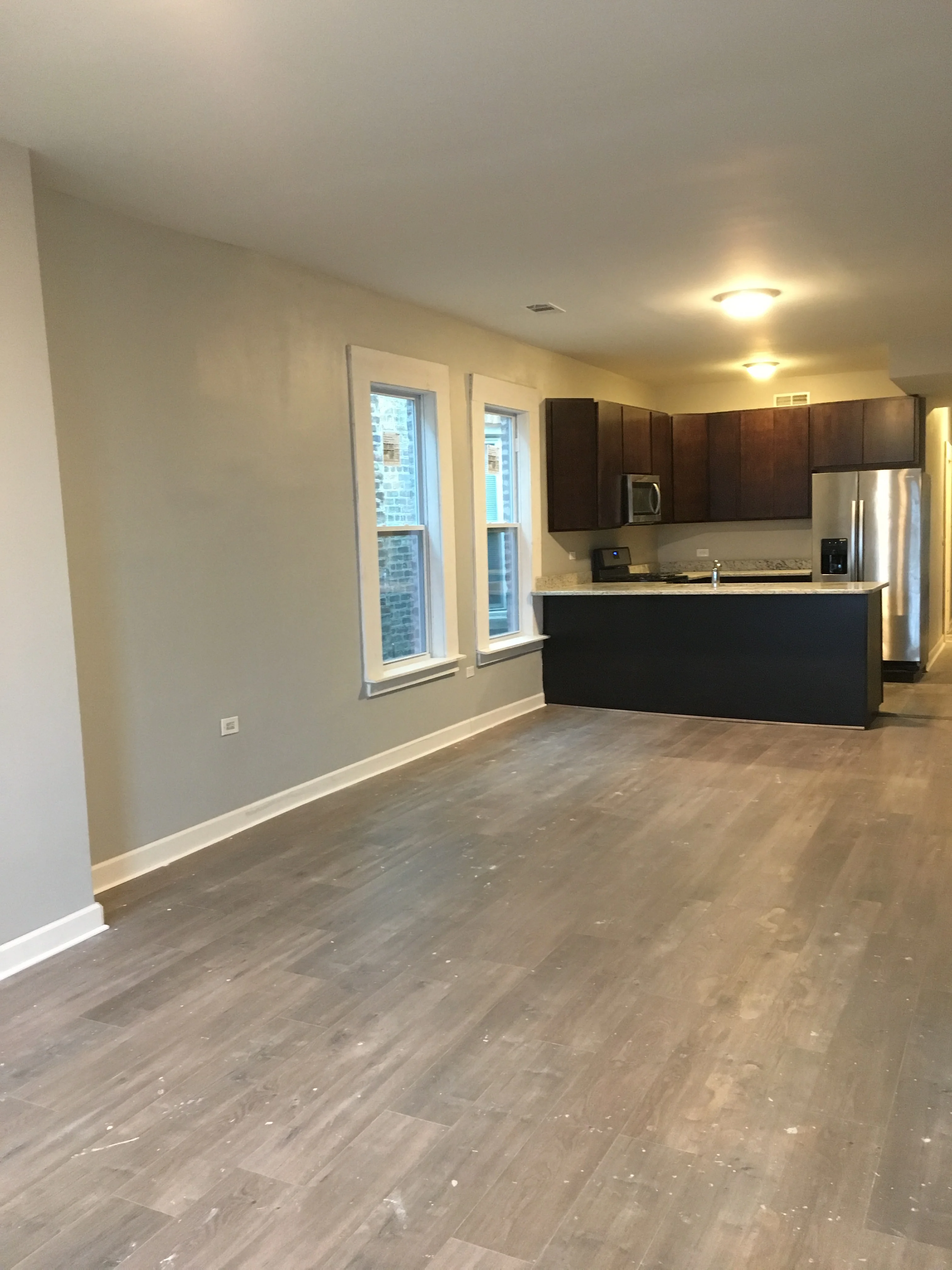 Modern kitchen with dark cabinets, stainless steel appliances, and light wood flooring