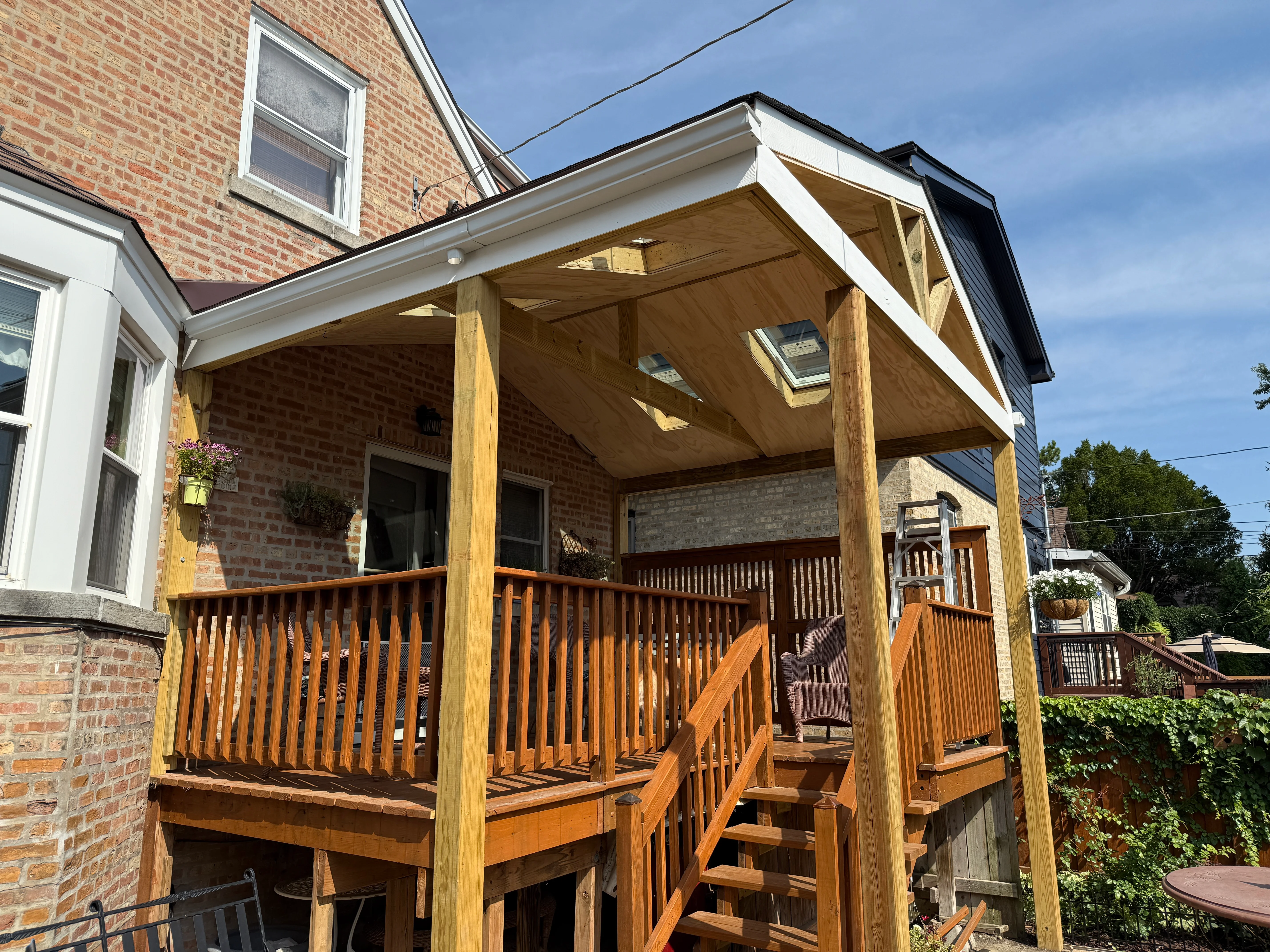 Wood pergola with skylights attached to brick home with composite deck and railings